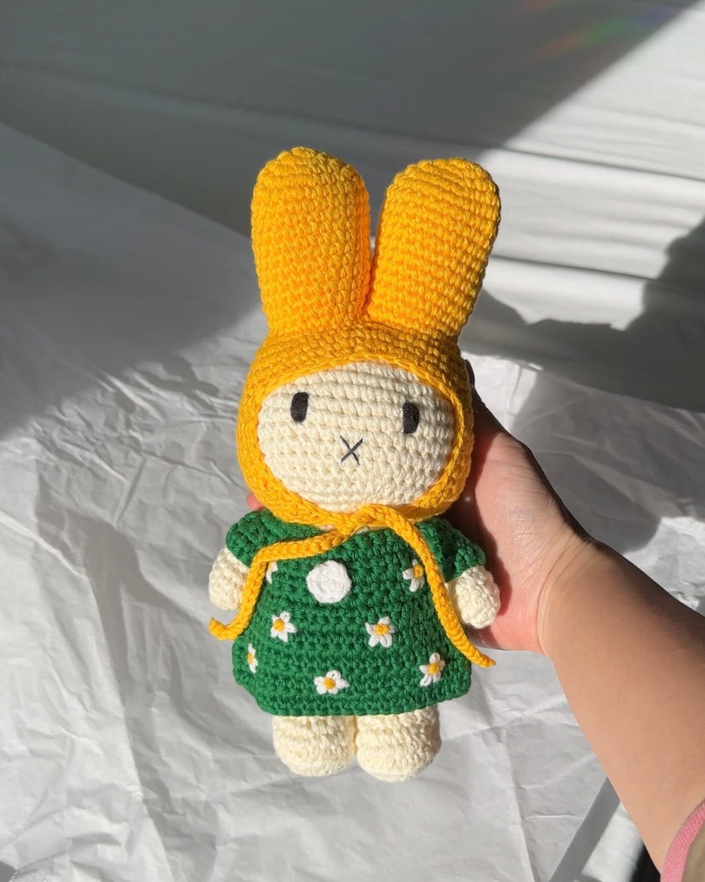 Close-up of handmade crochet Miffy bunny in yellow hood and green daisy dress