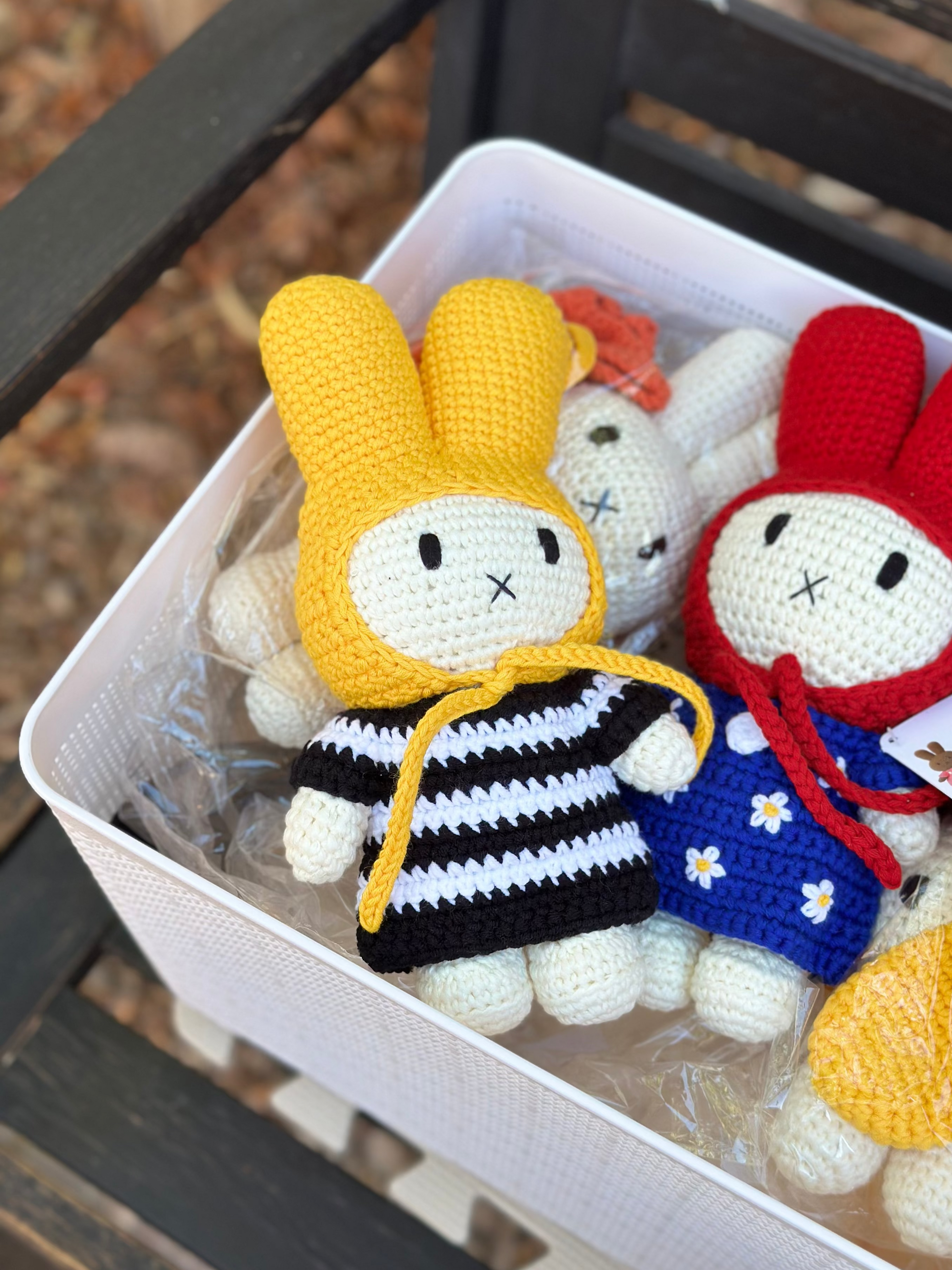 Close-up of a handmade crochet Miffy bunny doll wearing a yellow hood and black-and-white striped dress