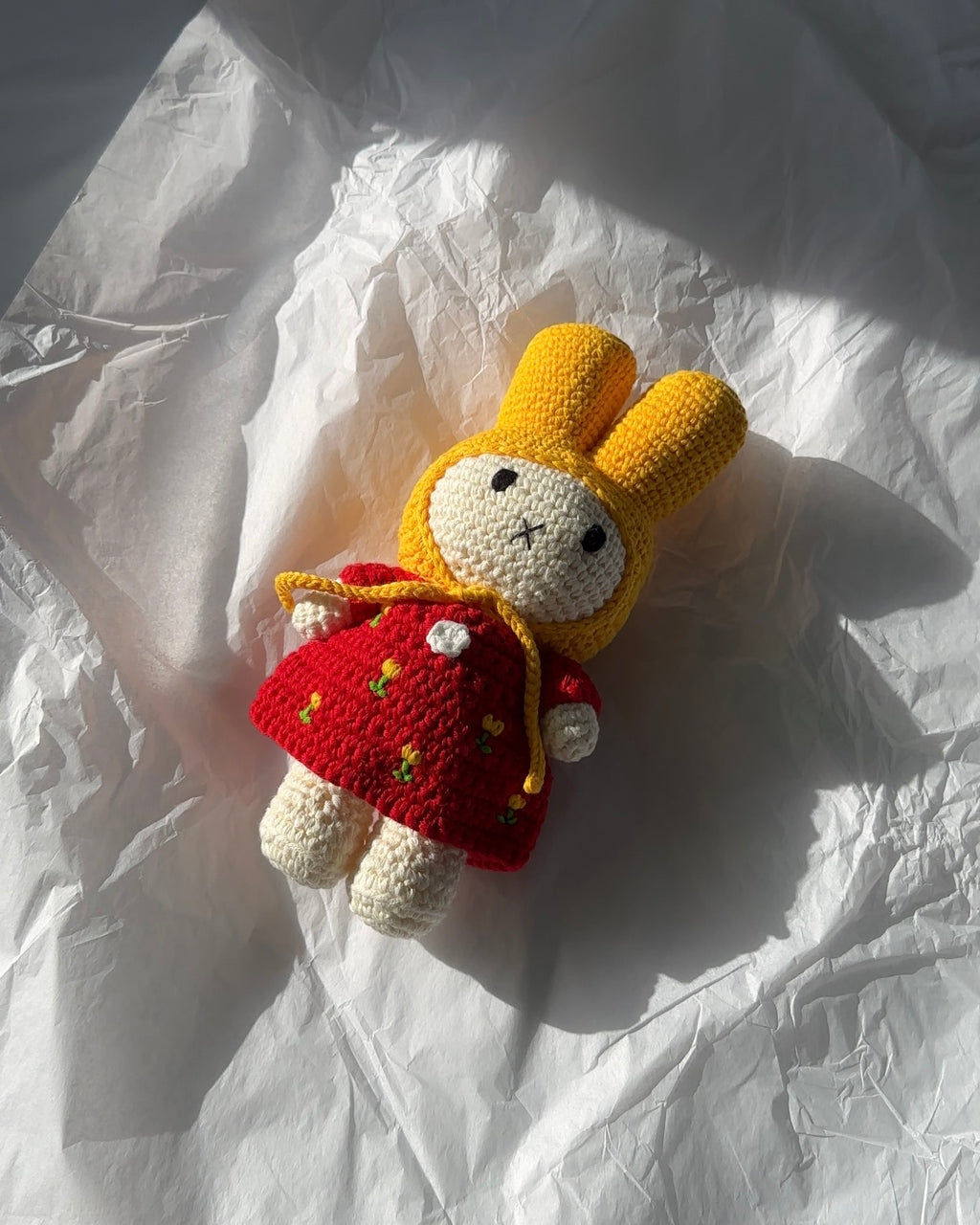Miffy crochet plush wearing a red tulip dress and yellow bonnet, hand-crocheted from cotton yarn and styled in natural light for cozy decor.