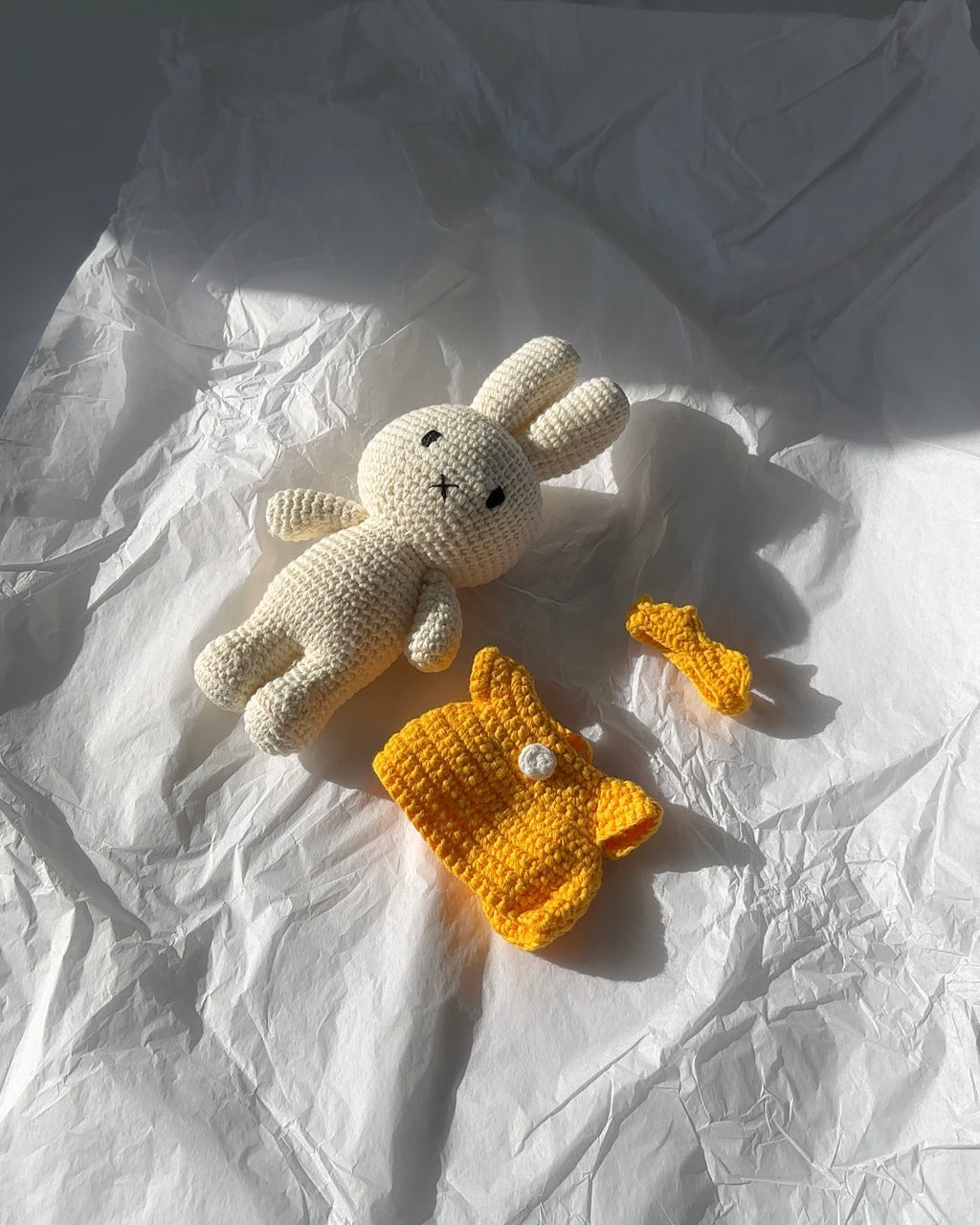 Hand-crocheted Miffy plush by Just Dutch with yellow dress and matching crown, made from cotton yarn with removable outfit pieces displayed in natural light.
