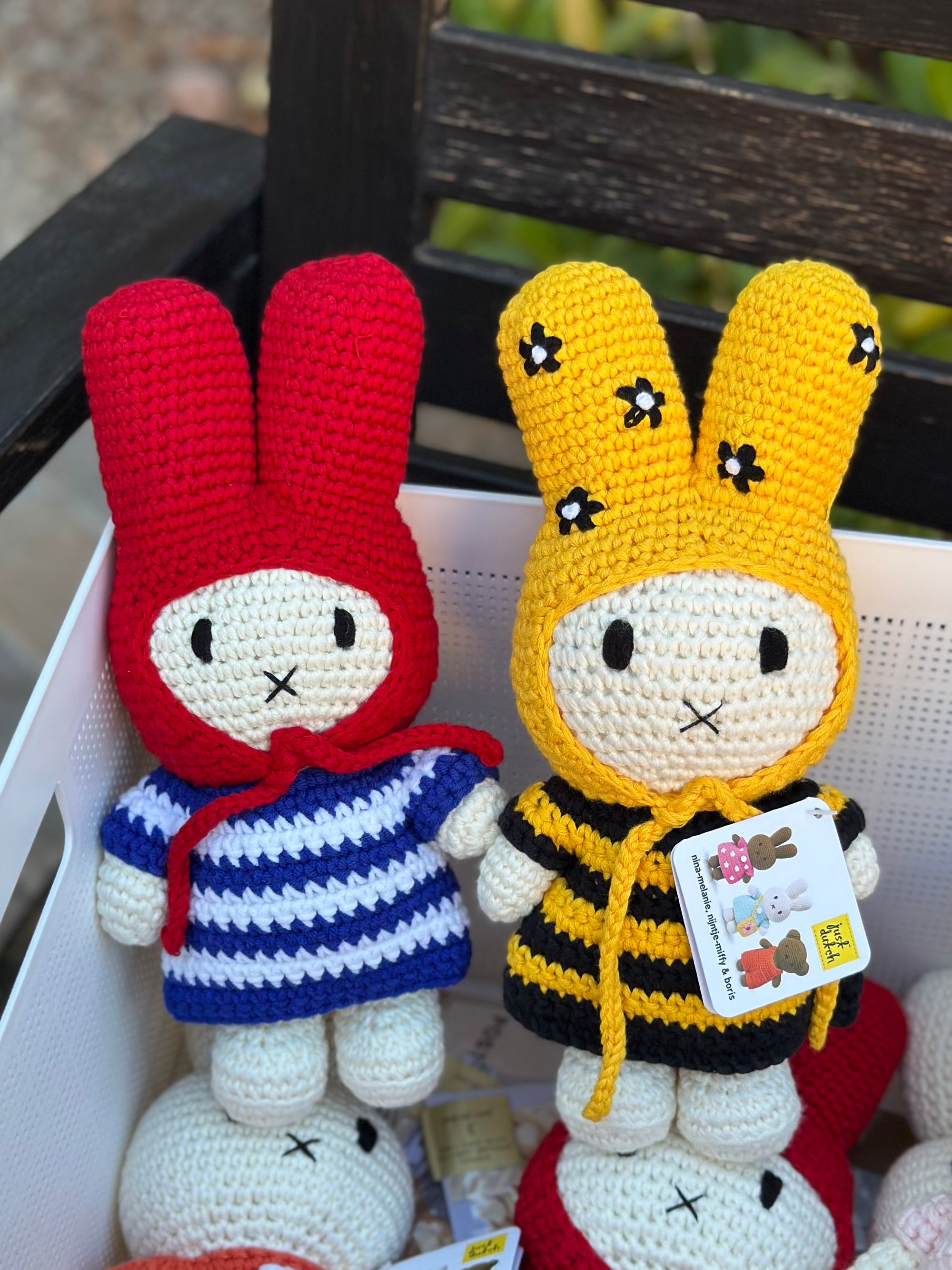 Handmade Miffy crochet plush in striped dress and red bonnet, displayed in a basket alongside another Miffy doll in a bee outfit.
