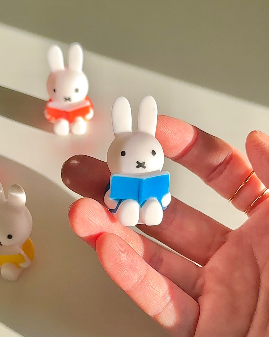 Close up of blue Miffy reading magnet holding a book, small Miffy fridge magnet detail
