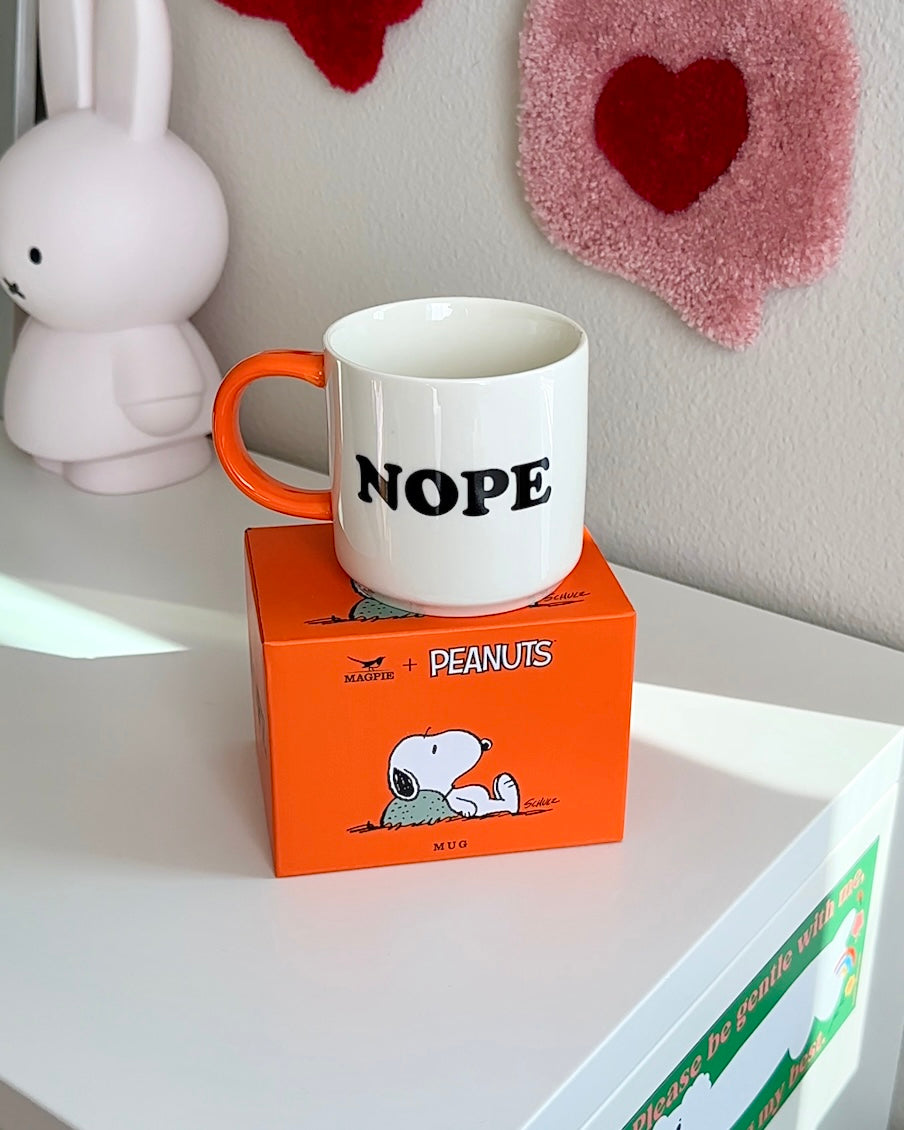 Snoopy “Nope” coffee mug displayed on its Peanuts collector box, white ceramic mug with orange handle and minimalist humor design.