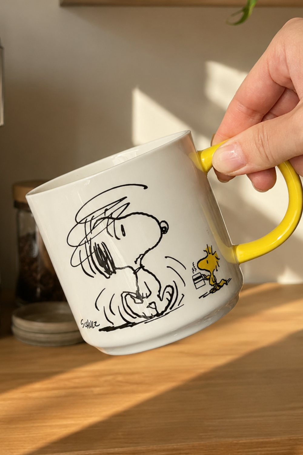 Snoopy Not Worth a Thing Before Coffee mug with yellow handle styled in a cozy coffee station with warm morning sunlight.