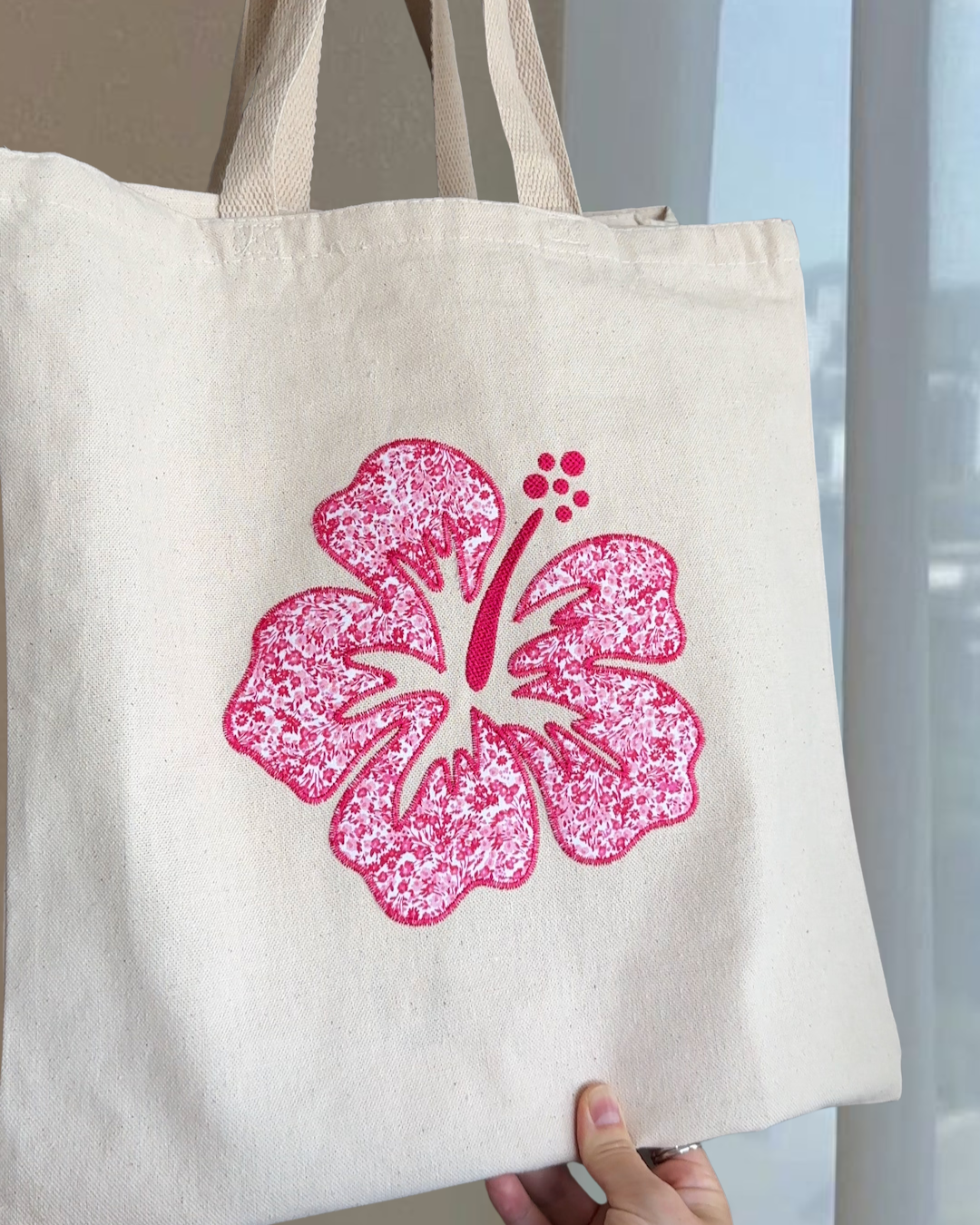 Close up of pink hibiscus patchwork embroidery on natural cotton canvas tote showing textured stitched floral detail