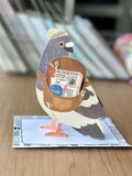 Side view of pigeon pop-up greeting card with 3D wings and messenger bag surprise.