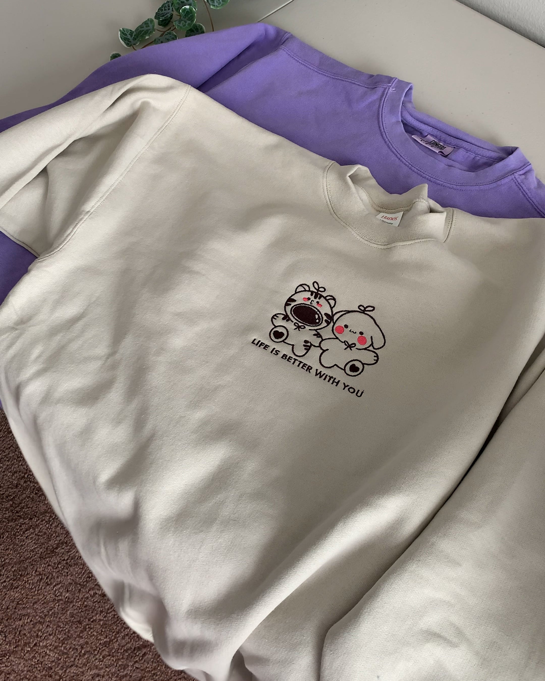 Sand beige oversized crewneck sweatshirt with small embroidered characters and the phrase “Life Is Better With You,” styled flat for a clean, minimal look.