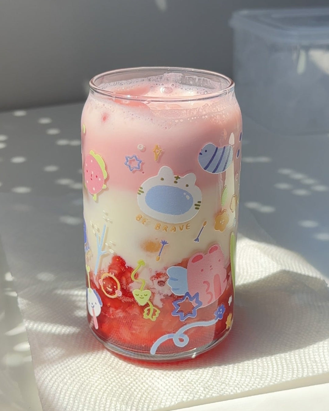 Secret Garden affirmation glass can filled with an iced drink, featuring gentle pastel artwork and encouraging phrases on a work-from-home desk.