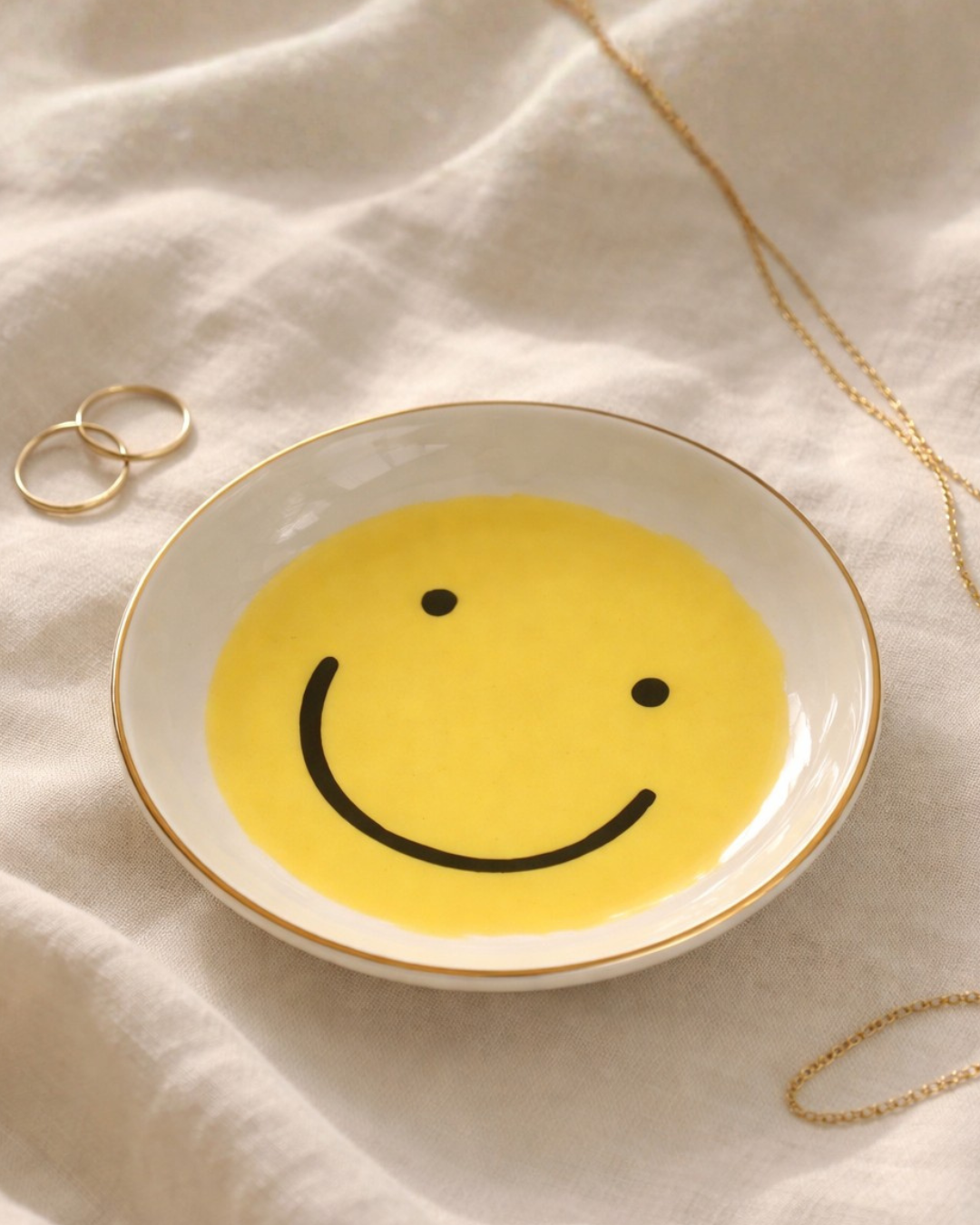 Smiley face jewelry dish on linen fabric with gold rings and necklace, cute trinket tray for rings earrings and small jewelry storage