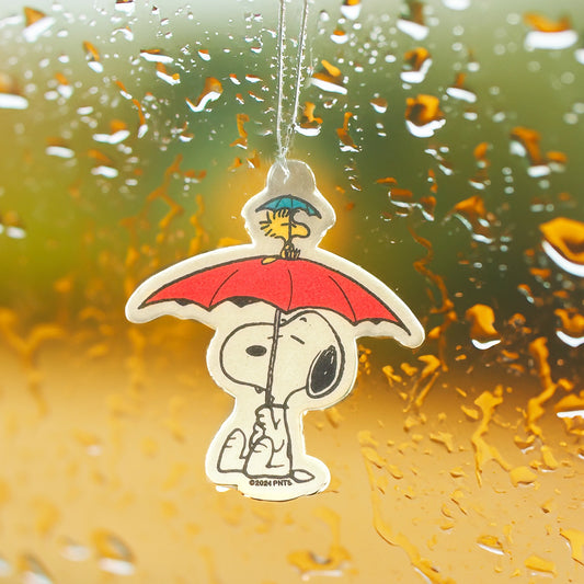 Snoopy umbrella air freshener hanging on a rainy car window. Cozy Peanuts accessory with Woodstock on top and sandalwood scent.