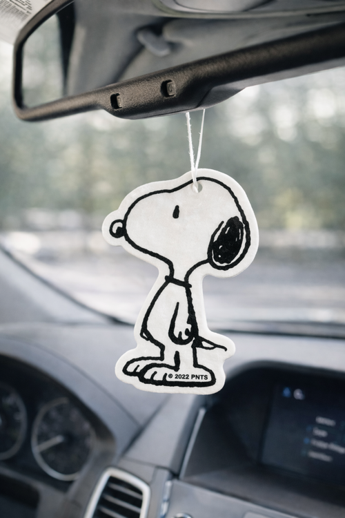 Snoopy car air freshener hanging from rearview mirror in car interior, cute Peanuts car accessory for aesthetic car decor.
