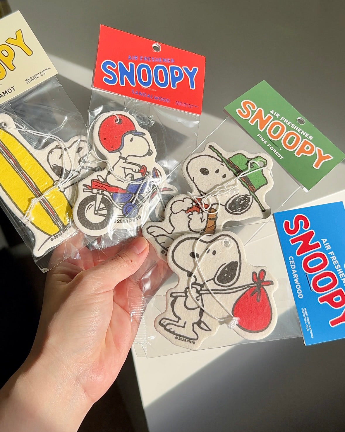 Snoopy cedarwood air freshener held in hand with other Peanuts characters