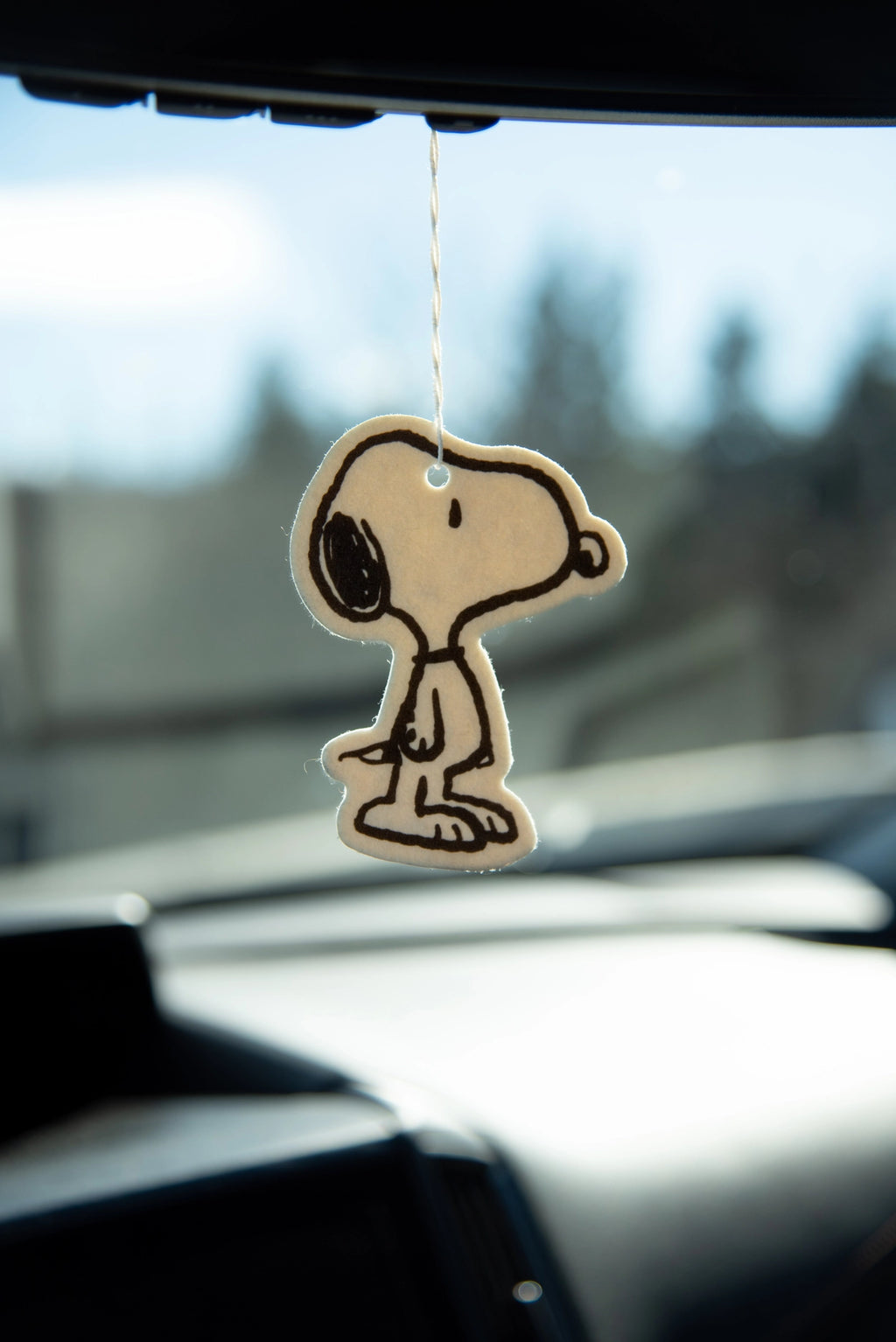 Minimalist Snoopy ‘Classic’ silhouette air freshener in coconut scent hanging from a rearview mirror in a car.