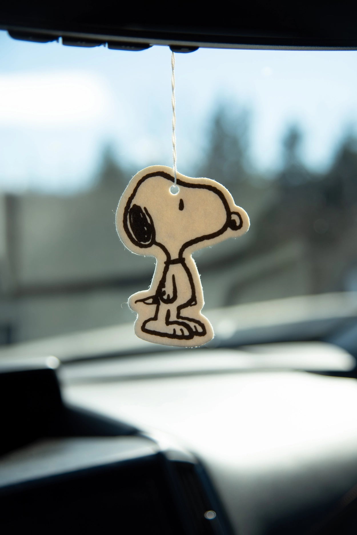 Minimalist Snoopy ‘Classic’ silhouette air freshener in coconut scent hanging from a rearview mirror in a car.