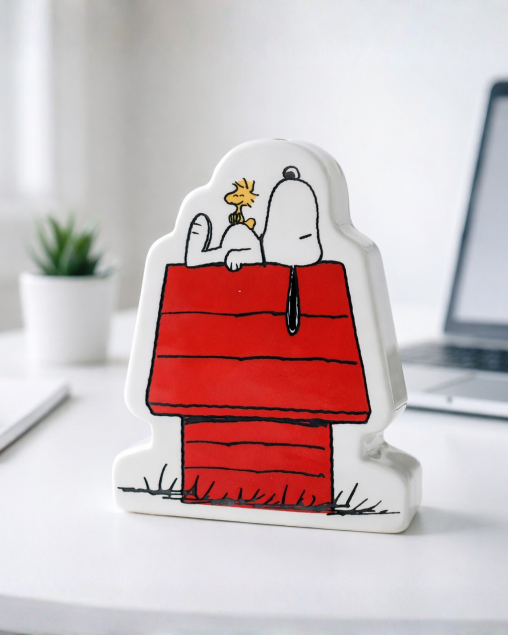 Ceramic Snoopy coin bank used as cute desk decor next to laptop and plant, nostalgic cartoon piggy bank for office desk or dorm room