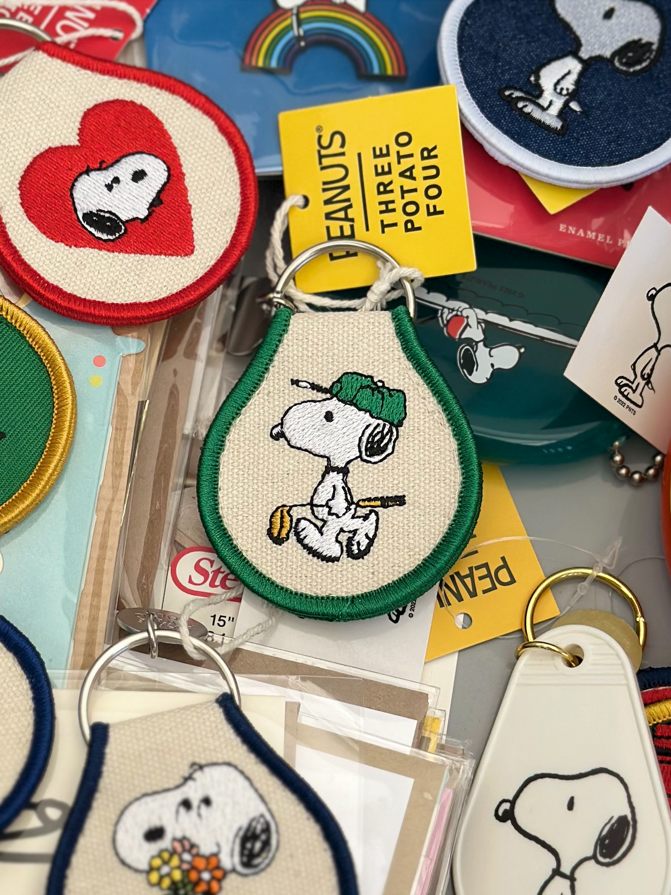 Embroidered Snoopy golf keychain on cream canvas with green trim, shown next to Snoopy heart design.