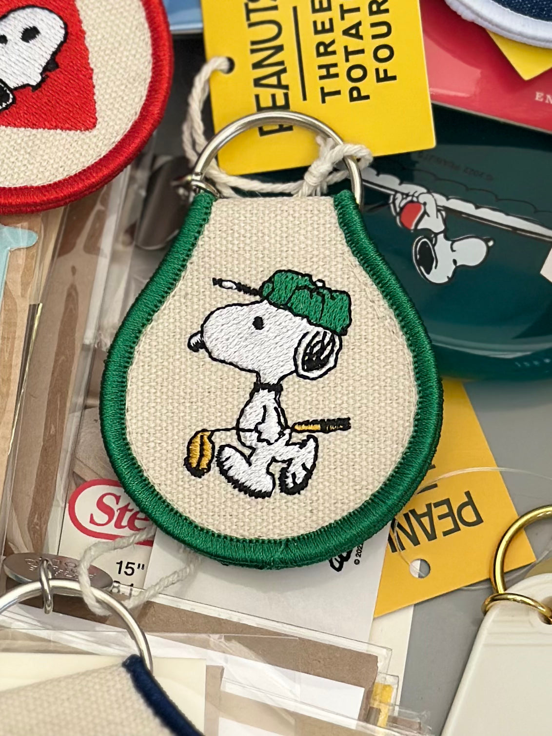 Embroidered Snoopy golf keychain on cream canvas with green trim and metal keyring.