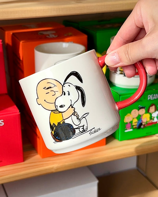 Official Snoopy “Happiness Is a Warm Puppy” ceramic mug featuring Charlie Brown hugging Snoopy, with red handle and gift-ready box