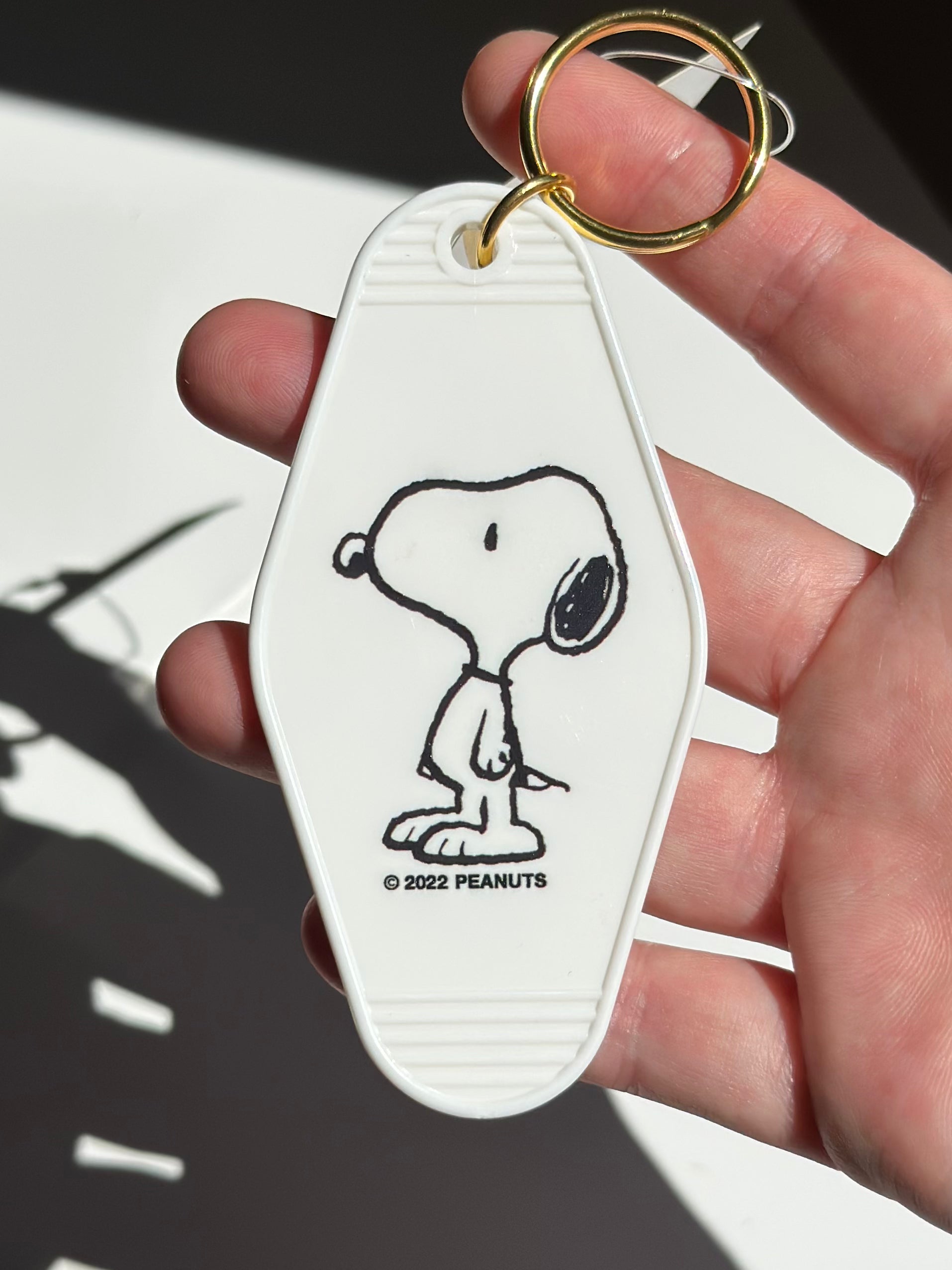 Retro Peanuts® Snoopy keychain shaped like a vintage hotel tag.
