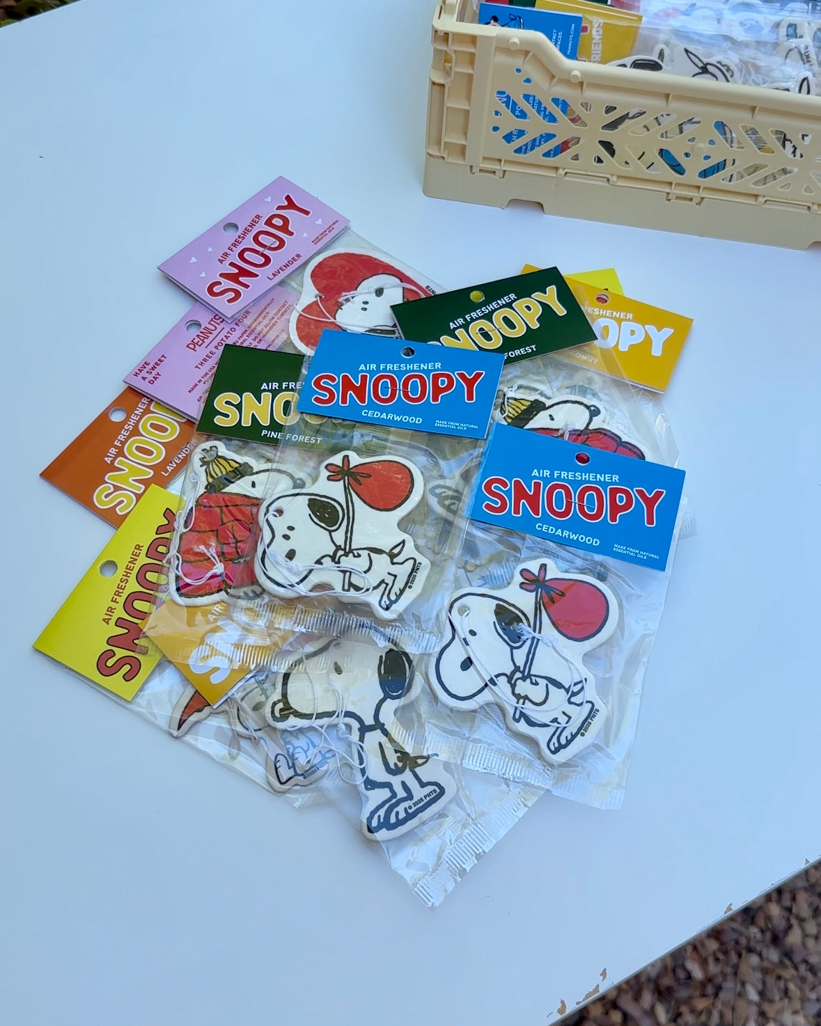 Multiple Snoopy air fresheners in assorted scents and designs, with Cedarwood nomad Snoopy holding a red bindle featured in front.