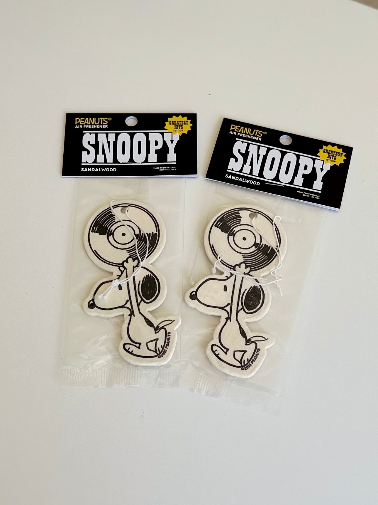 Two packaged Snoopy sandalwood air fresheners with vinyl record design, displayed flat on a white surface.