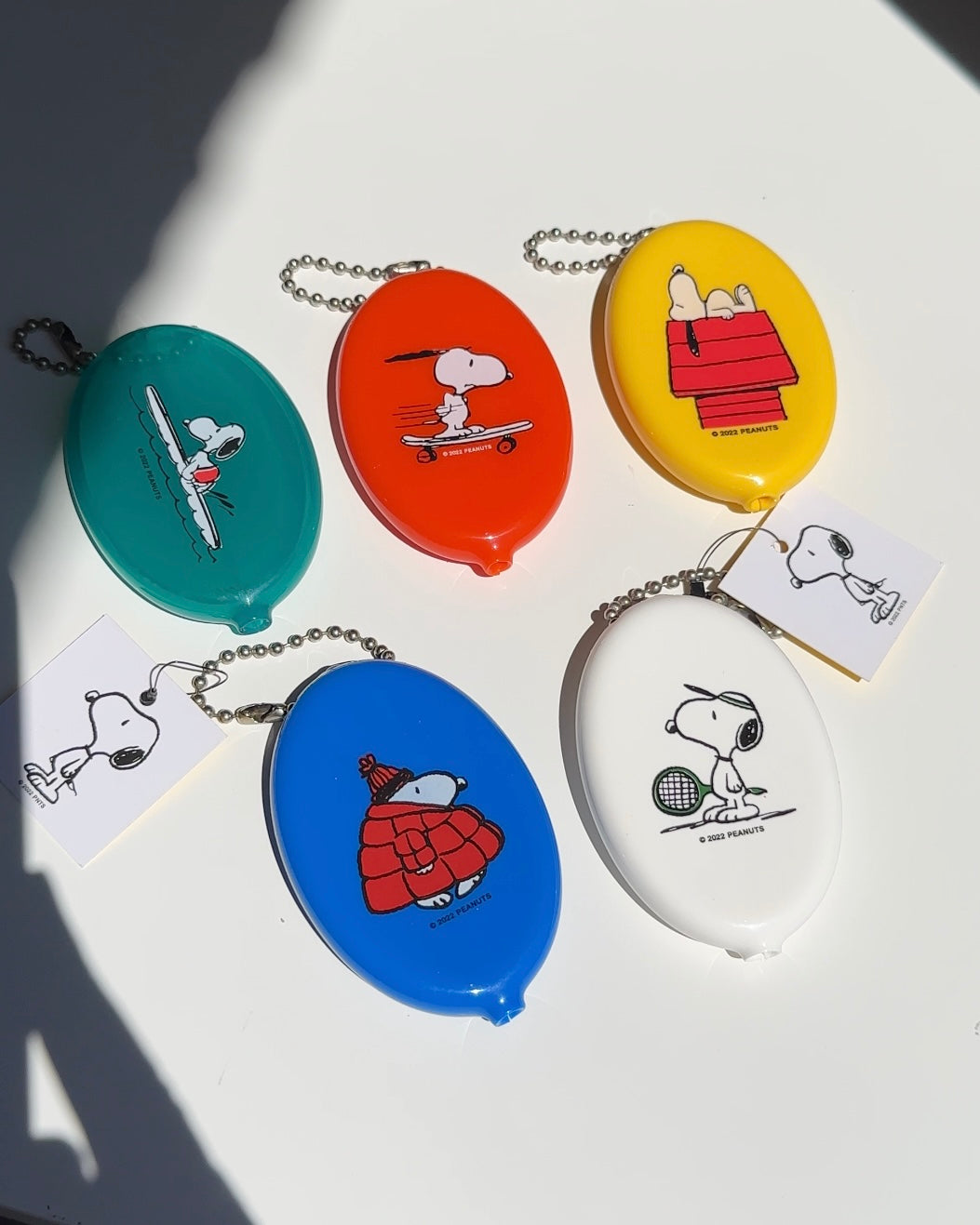 Set of colorful Snoopy vinyl coin pouches including bright orange skateboard design.
