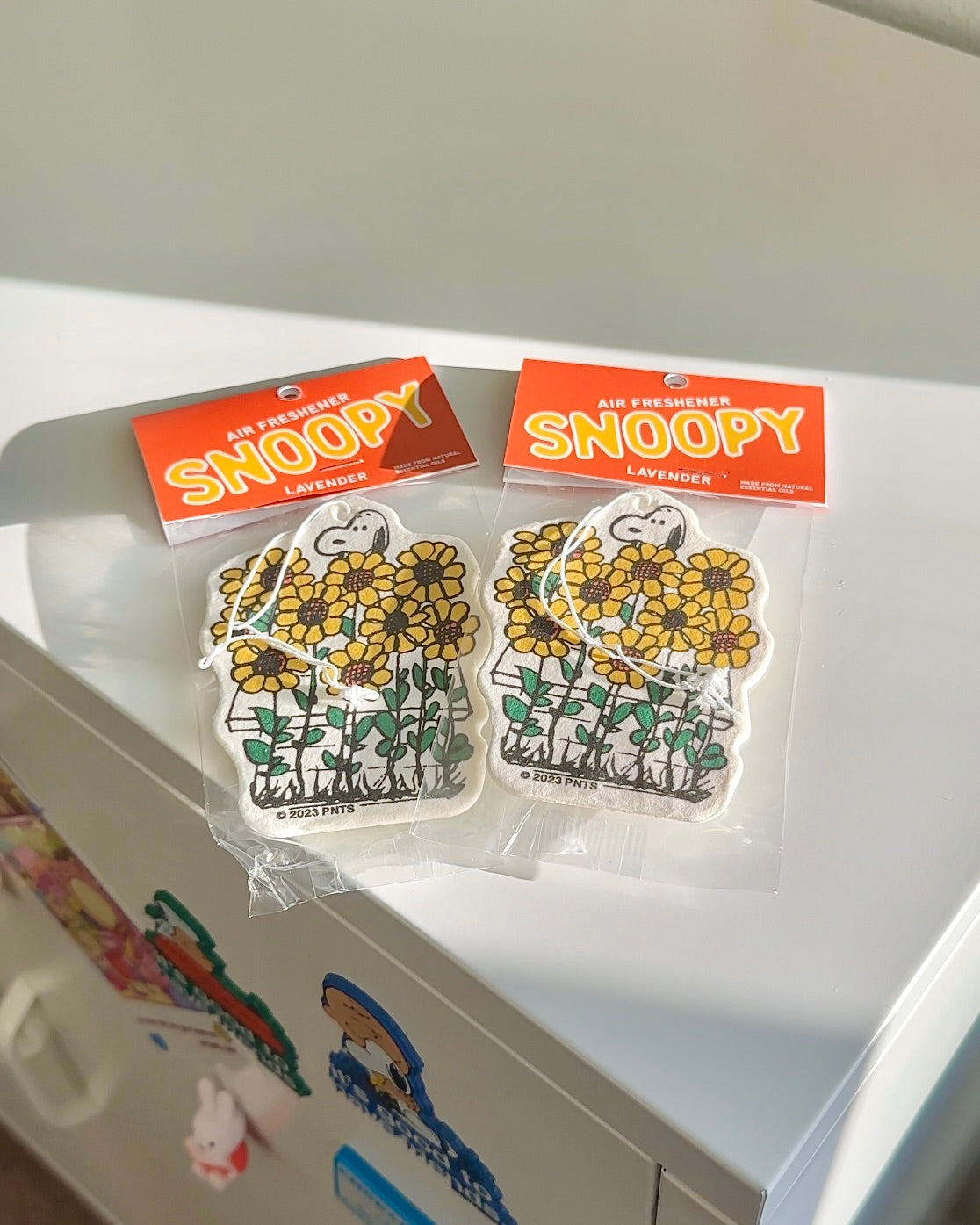 Two Snoopy sunflower air fresheners on a white surface. Lavender scented, perfect for cars or gifts for Peanuts fans and summer lovers.