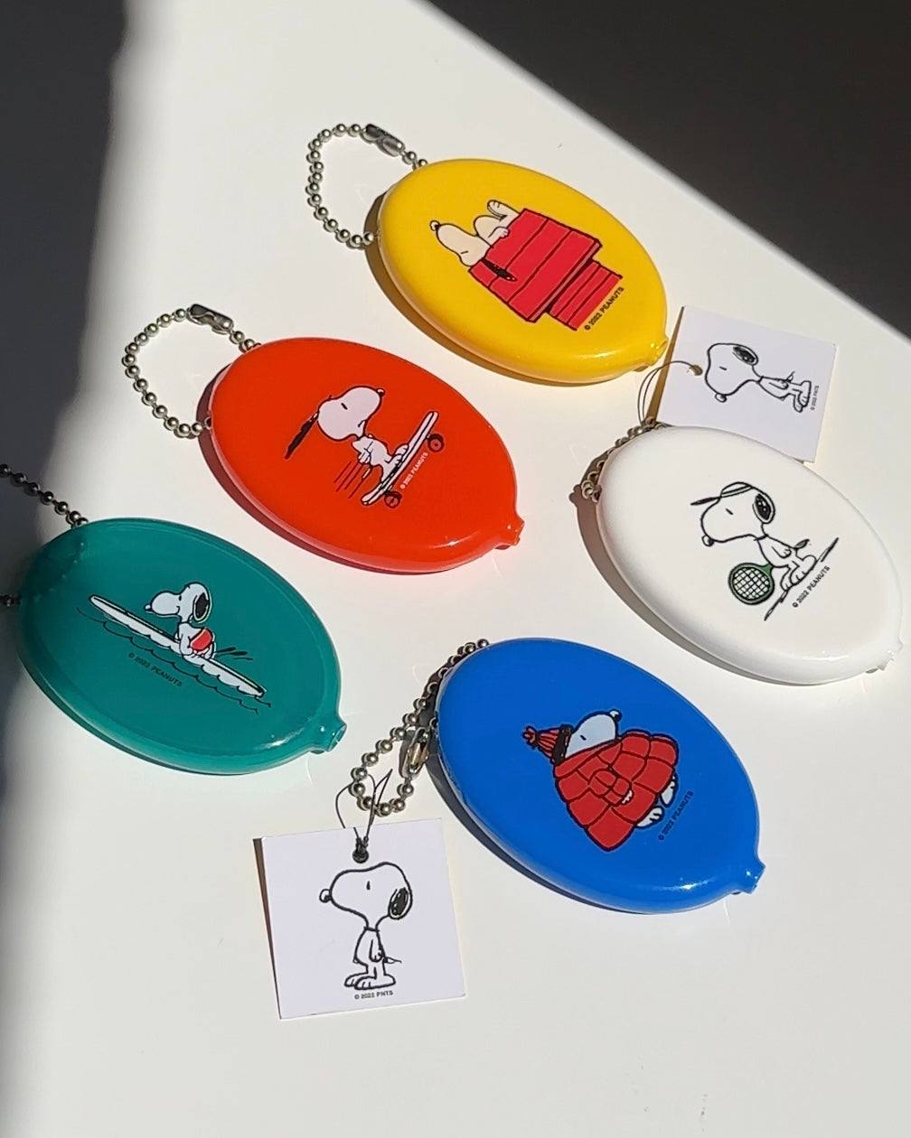 Set of colorful Snoopy coin pouches including turquoise surfboard design with ball chain keyrings.