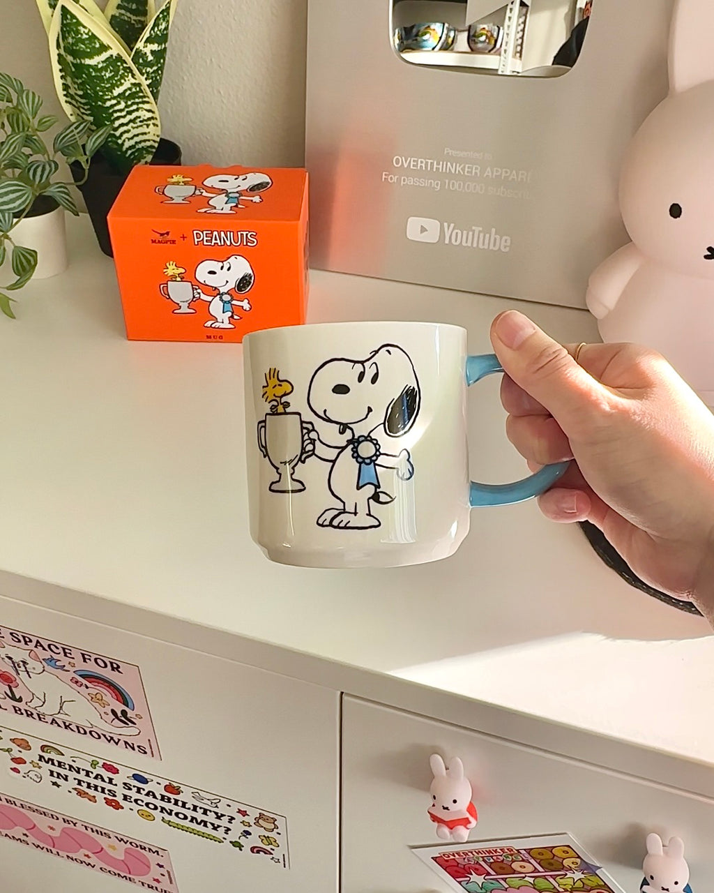Hand holding Snoopy Top Dog mug in a cozy room setup with Miffy magnets and cute decor