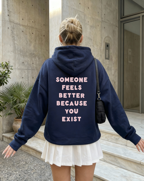Back view of a navy zip up hoodie with the affirmation "Someone feels better because you exist" printed in soft pink lettering