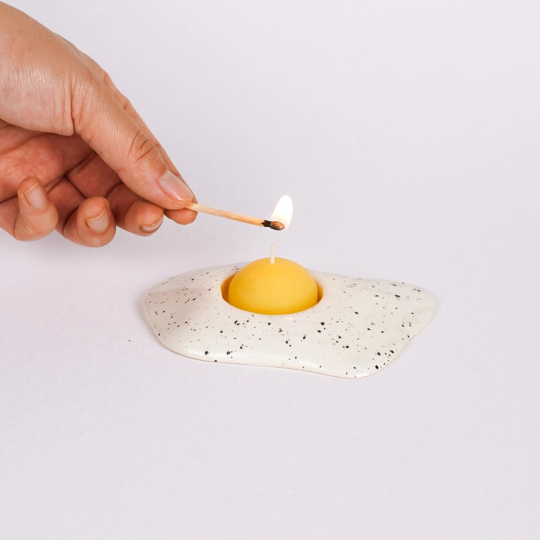 Ceramic sunny side up egg tealight holder with yellow beeswax yolk candle being lit