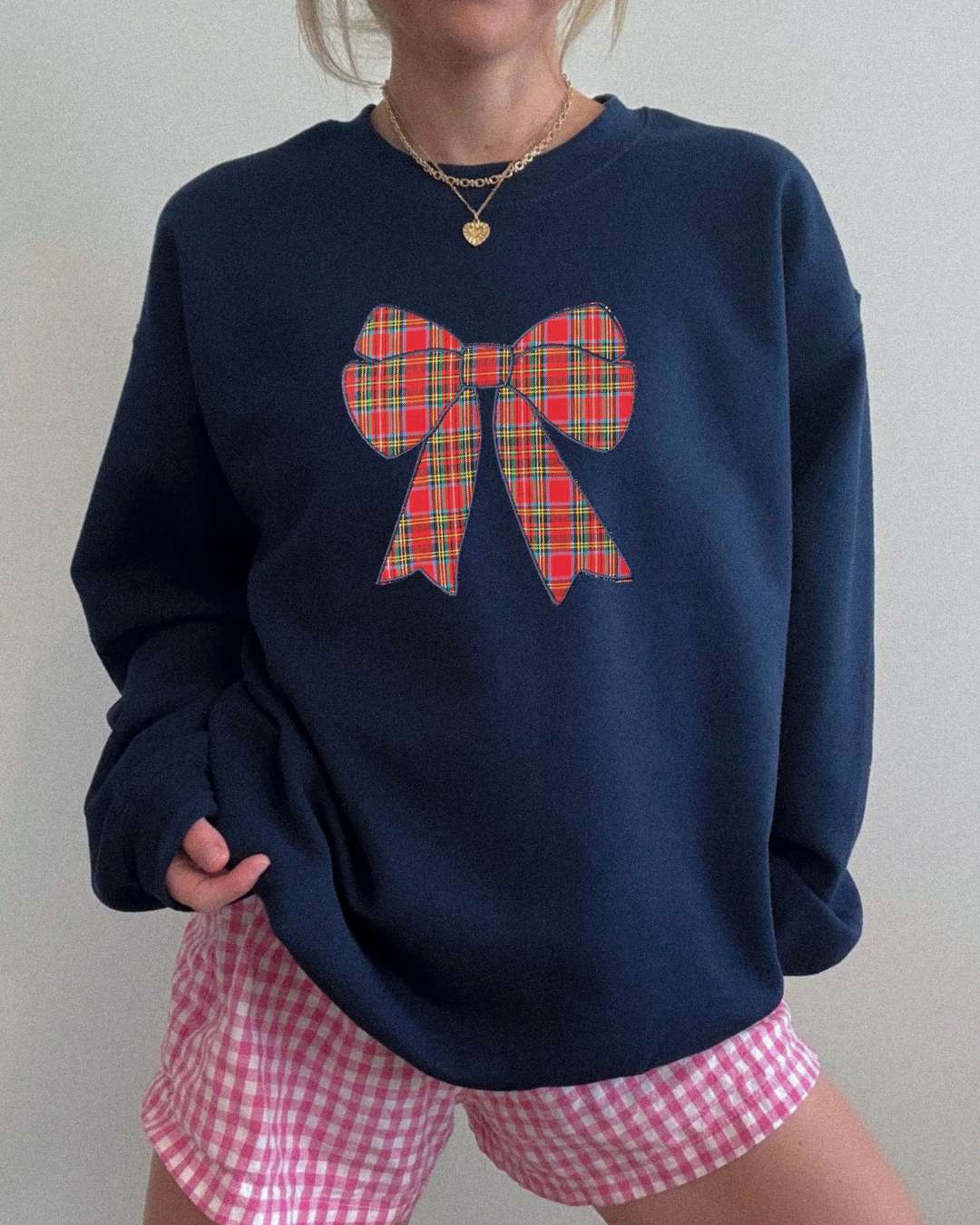 Navy blue oversized Christmas sweatshirt with embroidered red tartan bow, cozy holiday crewneck styled for classic festive winter outfits