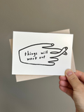 Minimalist encouragement card with simple hand illustration and the phrase ‘Things will work out,’ paired with light beige envelope.