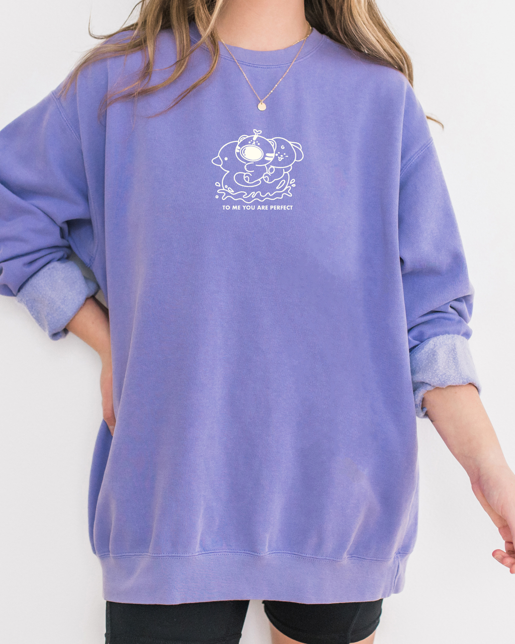 Model wearing a violet embroidered affirmation sweatshirt with a small white design that reads ‘To me, you are perfect,’ offering a soft, comforting, minimalist look