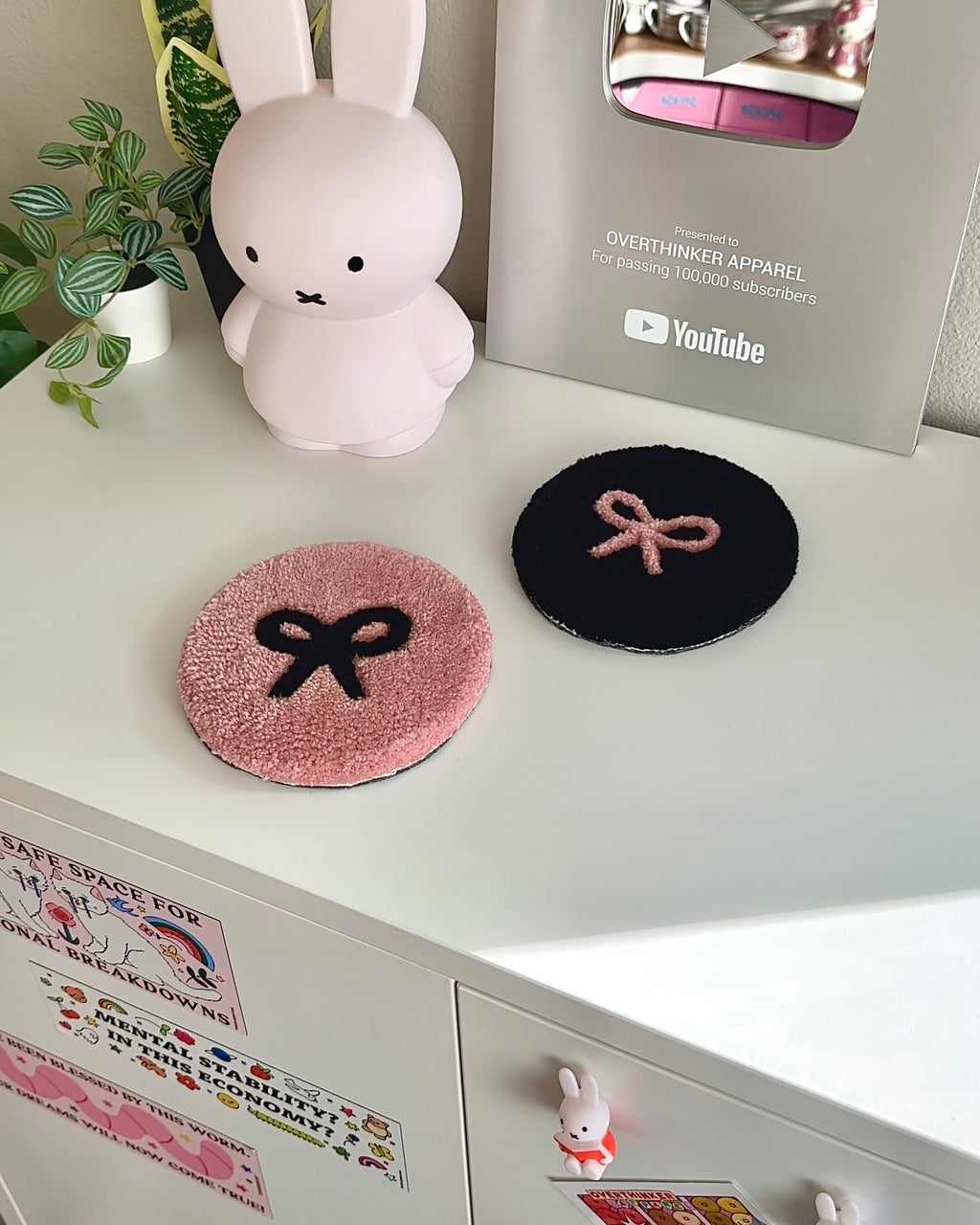 Pink and black tufted bow coasters on white desk next to decor