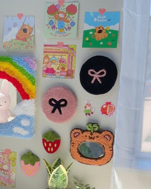 Pink and black bow rugs used as wall decor on gallery wall with cute art and plush accents