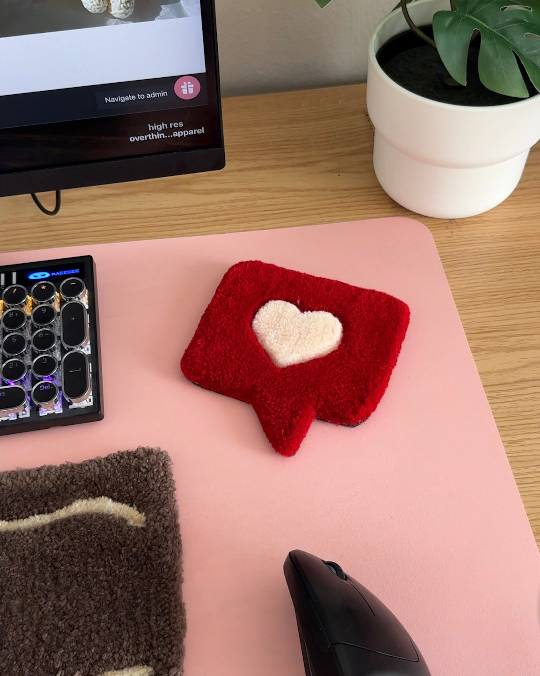 Tufted red heart coaster on pink desk setup beside keyboard and mouse