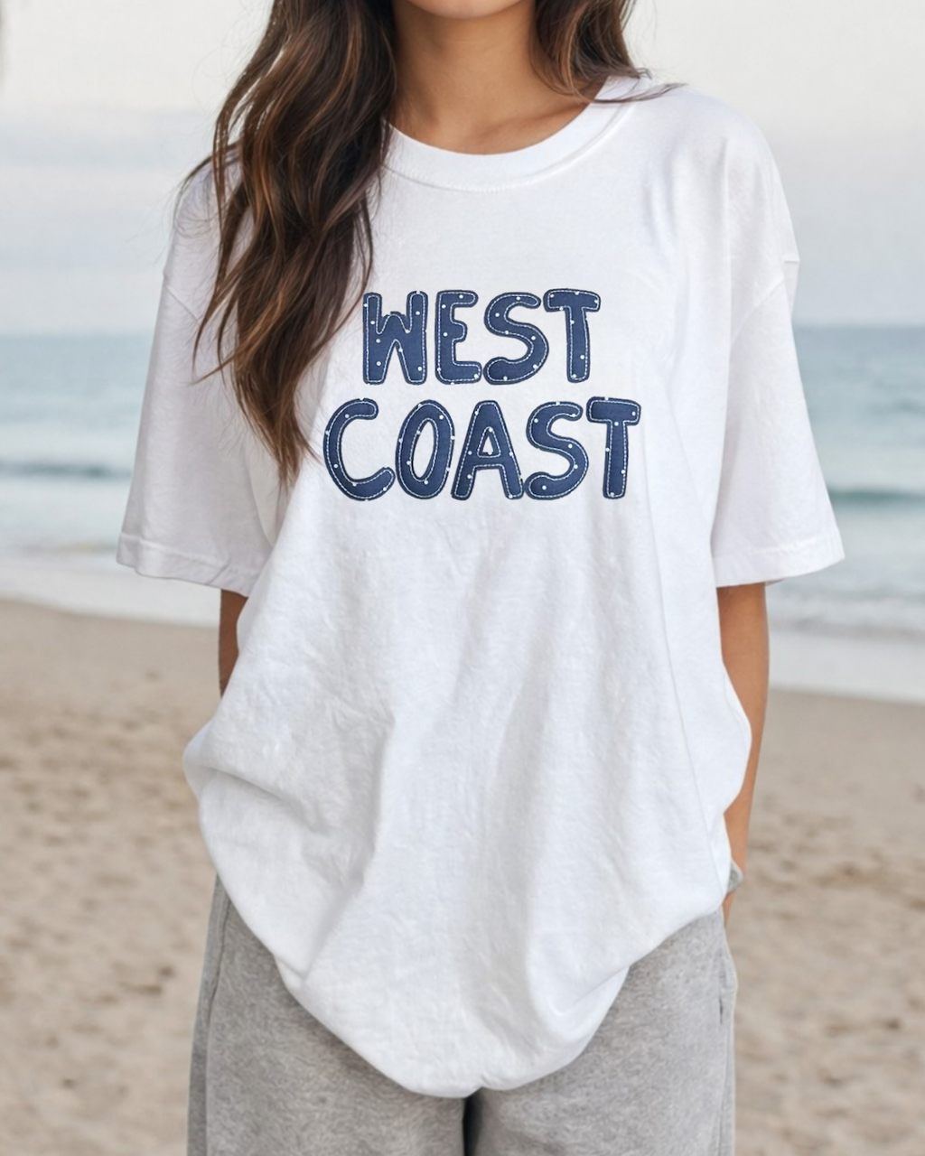 oversized white west coast graphic t shirt worn on beach casual coastal outfit relaxed summer look