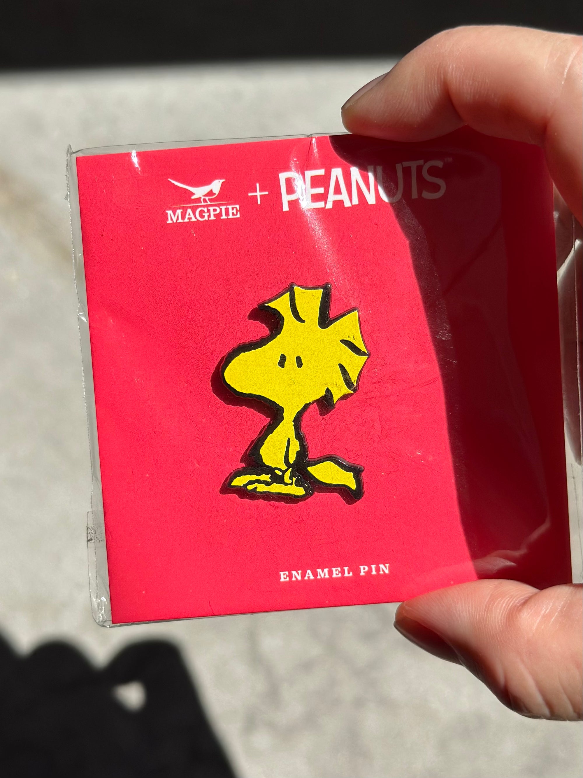 Close-up of Woodstock enamel pin on official red Peanuts® card