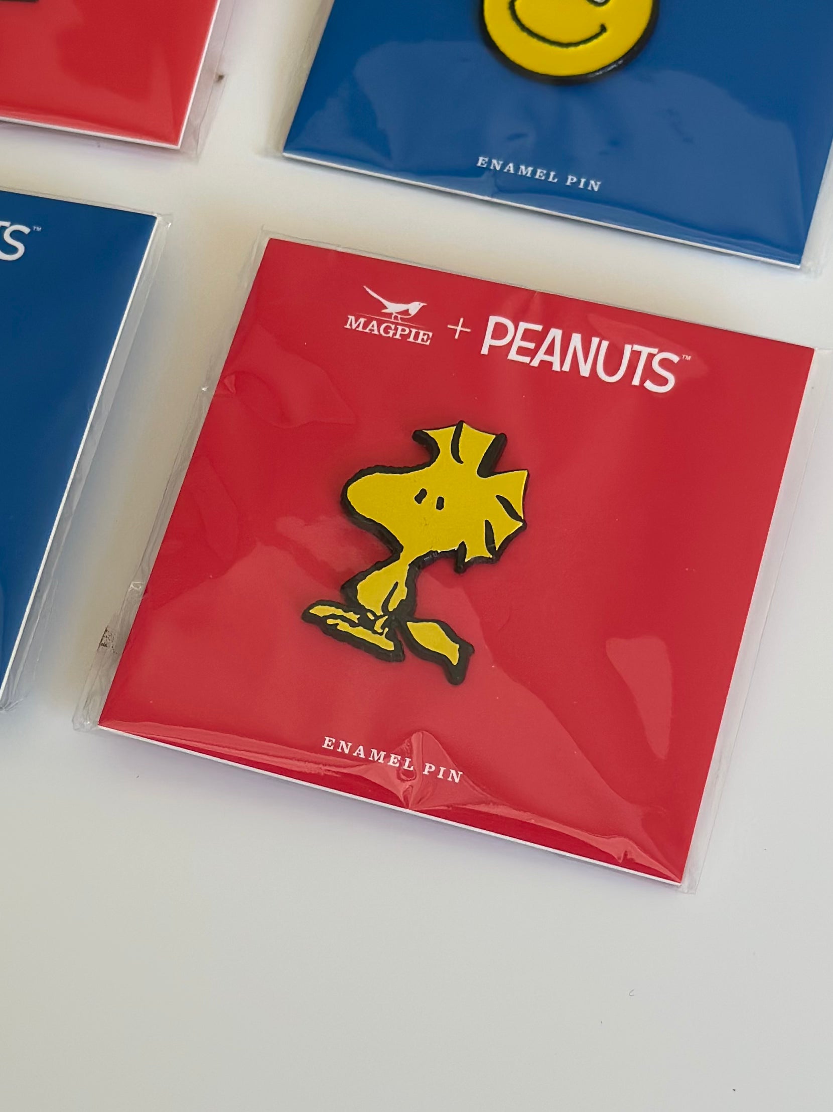 Woodstock enamel pin displayed on red Peanuts® card, flat lay style