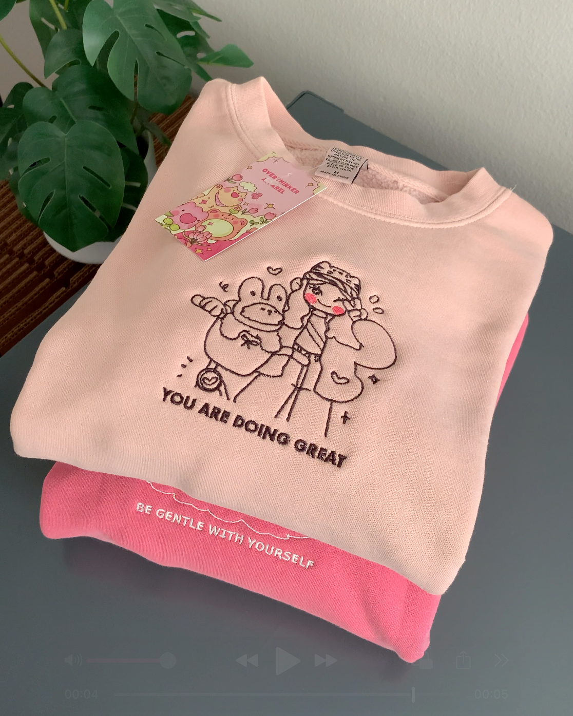 Stacked embroidered sweatshirts showing dusty pink “You Are Doing Great” crewneck paired with a pink “Be Gentle With Yourself” sweatshirt
