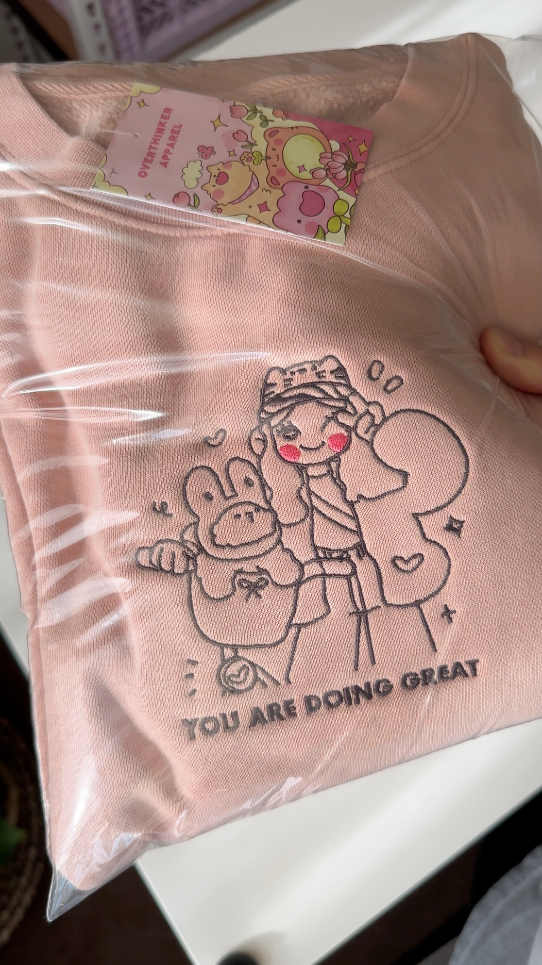 Dusty pink “You Are Doing Great” embroidered sweatshirt folded and packaged in a clear bag, ready for gifting or shipping