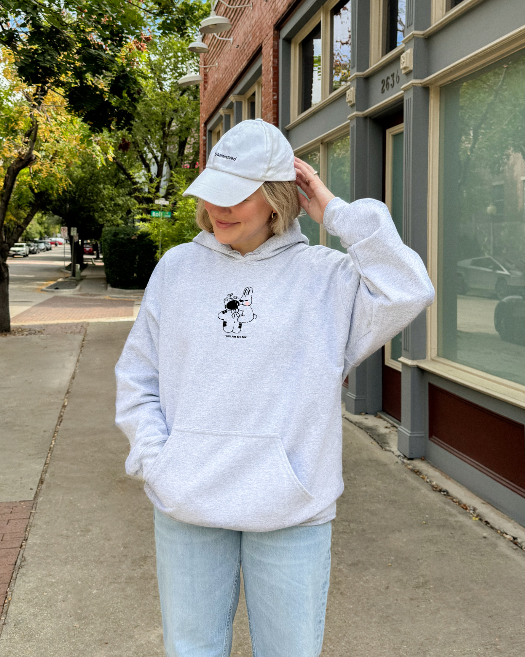 Light gray embroidered hoodie with “You Are My Fav” text and small character design, worn casually outdoors