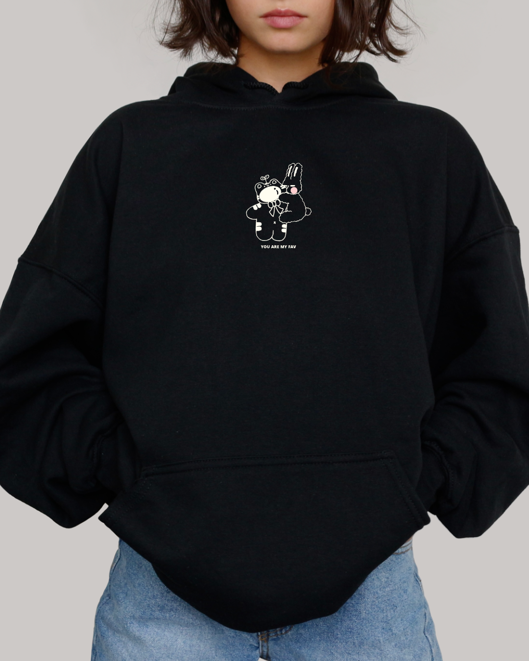 Black embroidered hoodie featuring a small “You Are My Fav” design with two gentle characters, shown in a clean minimal studio setting